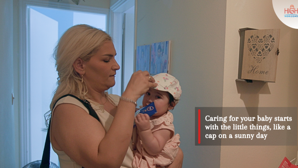 Woman Strapping a hat to her baby's head as a heat protective measure