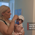 Woman Strapping a hat to her baby's head as a heat protective measure