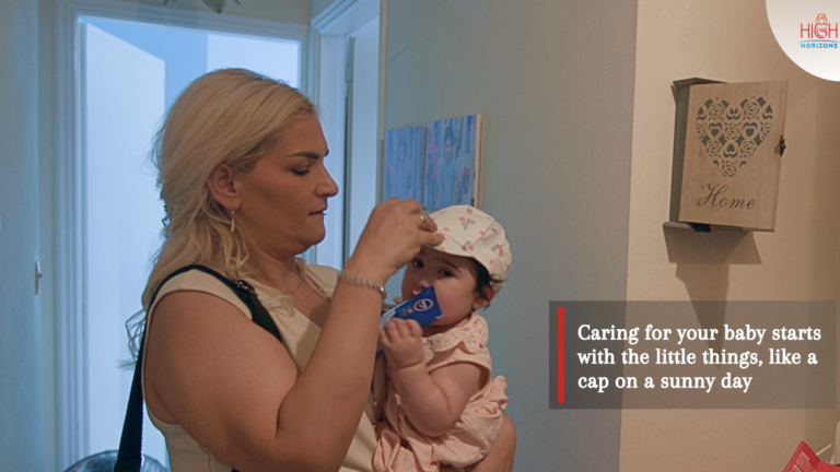 Woman Strapping a hat to her baby's head as a heat protective measure